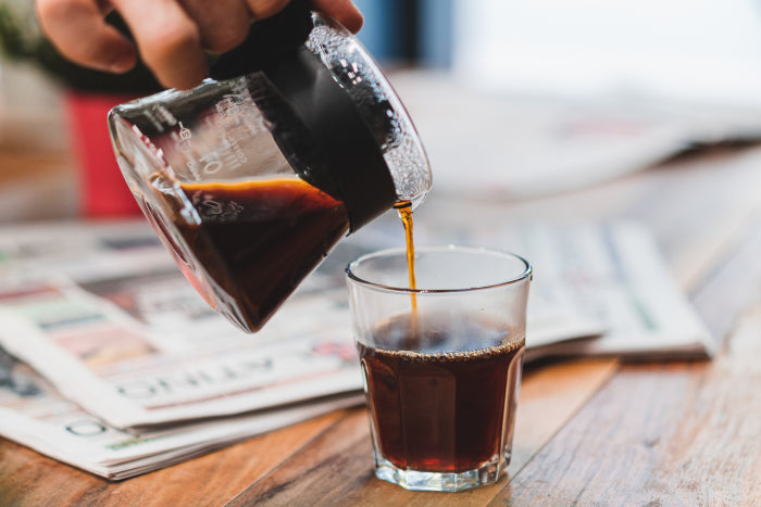 Barista pouring V60 coffee into glass for customer